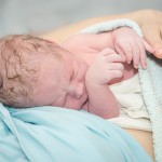 Young beautiful woman with a newborn baby after birth